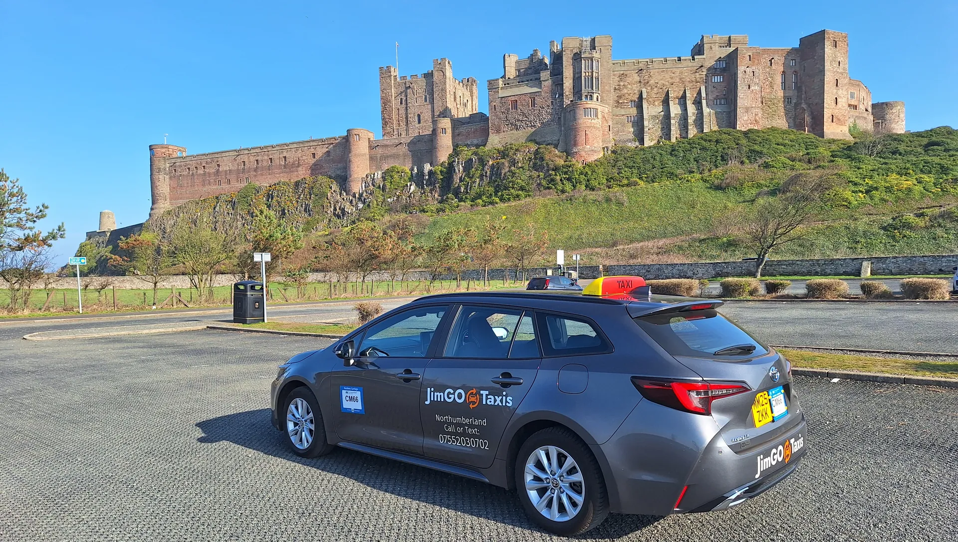 The JimGO taxi parked below Bamburgh Castle