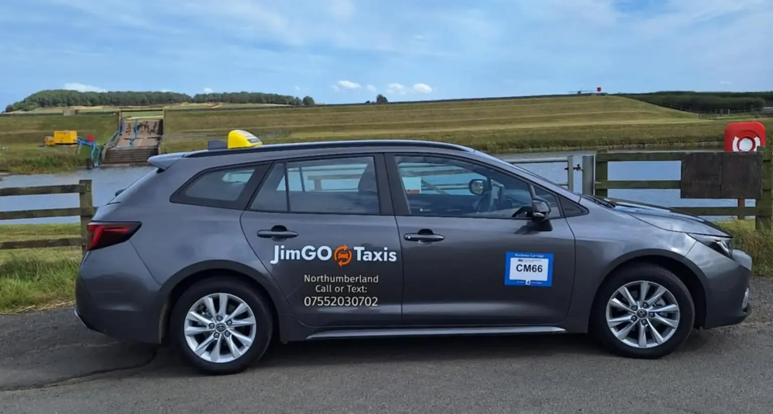 Side view of the JimGO taxi beside a reservoir on a sunny day