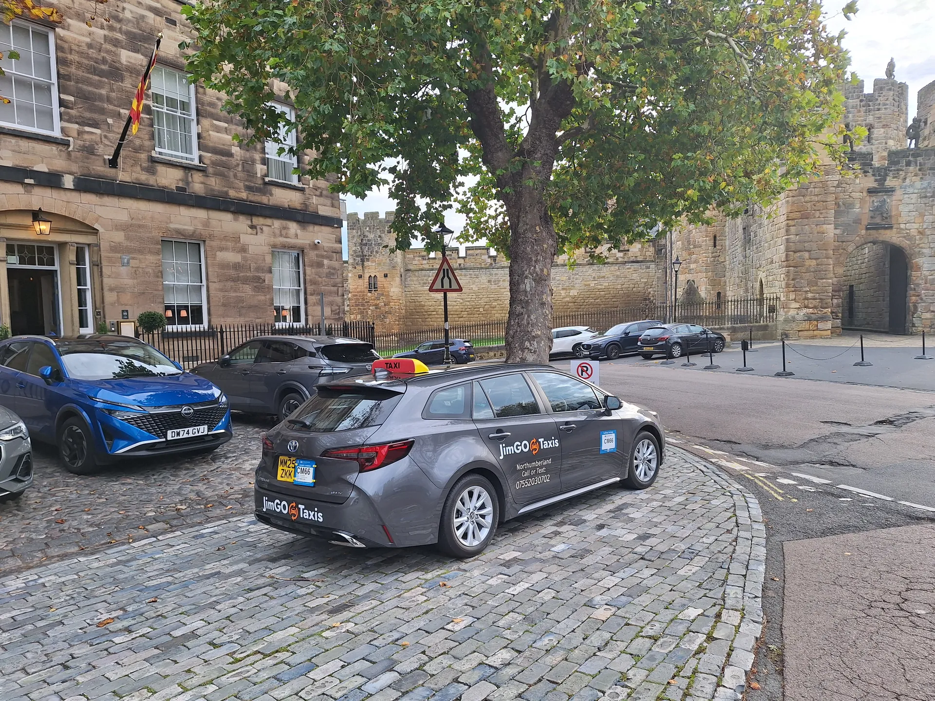 The JimGO taxi on a cobbled street beside old stone buildings